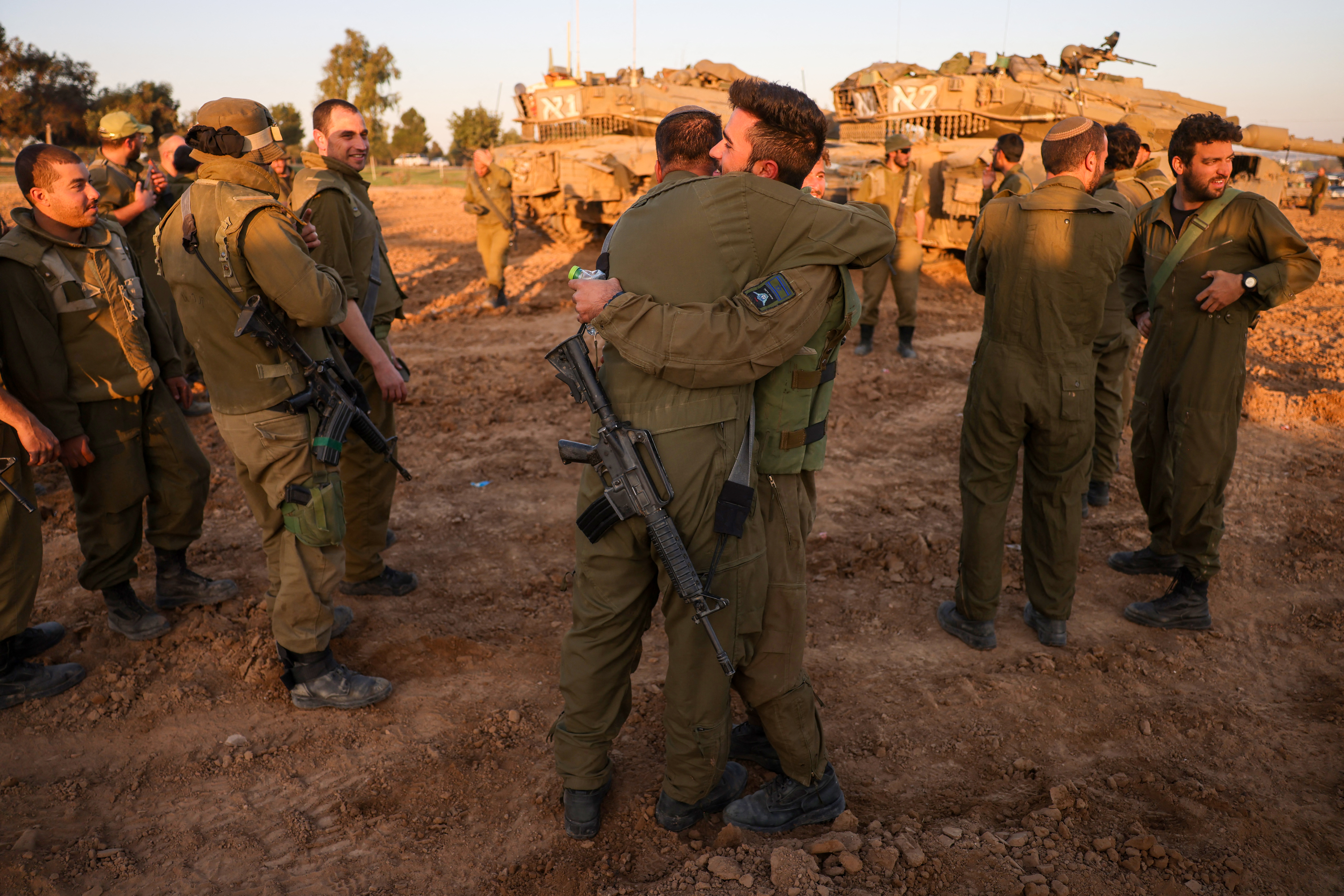 Soldaten umarmen sich am Mittwoch in der Nähe von Panzern, die an Israels Südgrenze zum Gazastreifen stationiert sind, als das Waffenstillstandsabkommen in seinen sechsten Tag ging