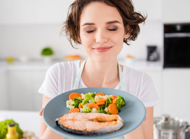 Frau mit gesundem Teller Lachs und Gemüse, Konzept von Lebensmitteln, die braunes Fett zur Gewichtsabnahme anregen