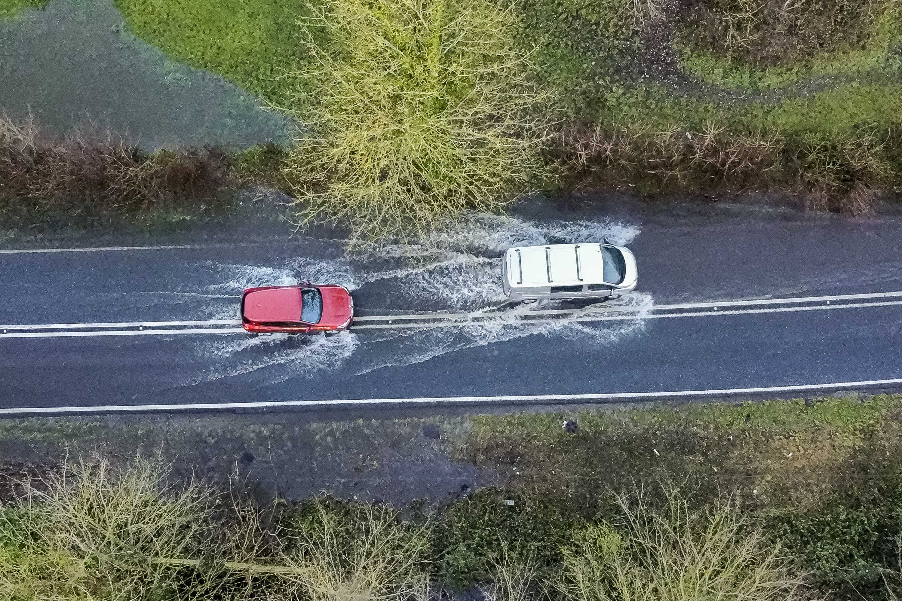 Am Sonntag fahren Fahrzeuge auf der A35 in der Nähe von Winterbourne Abbas in Dorset durch Hochwasser