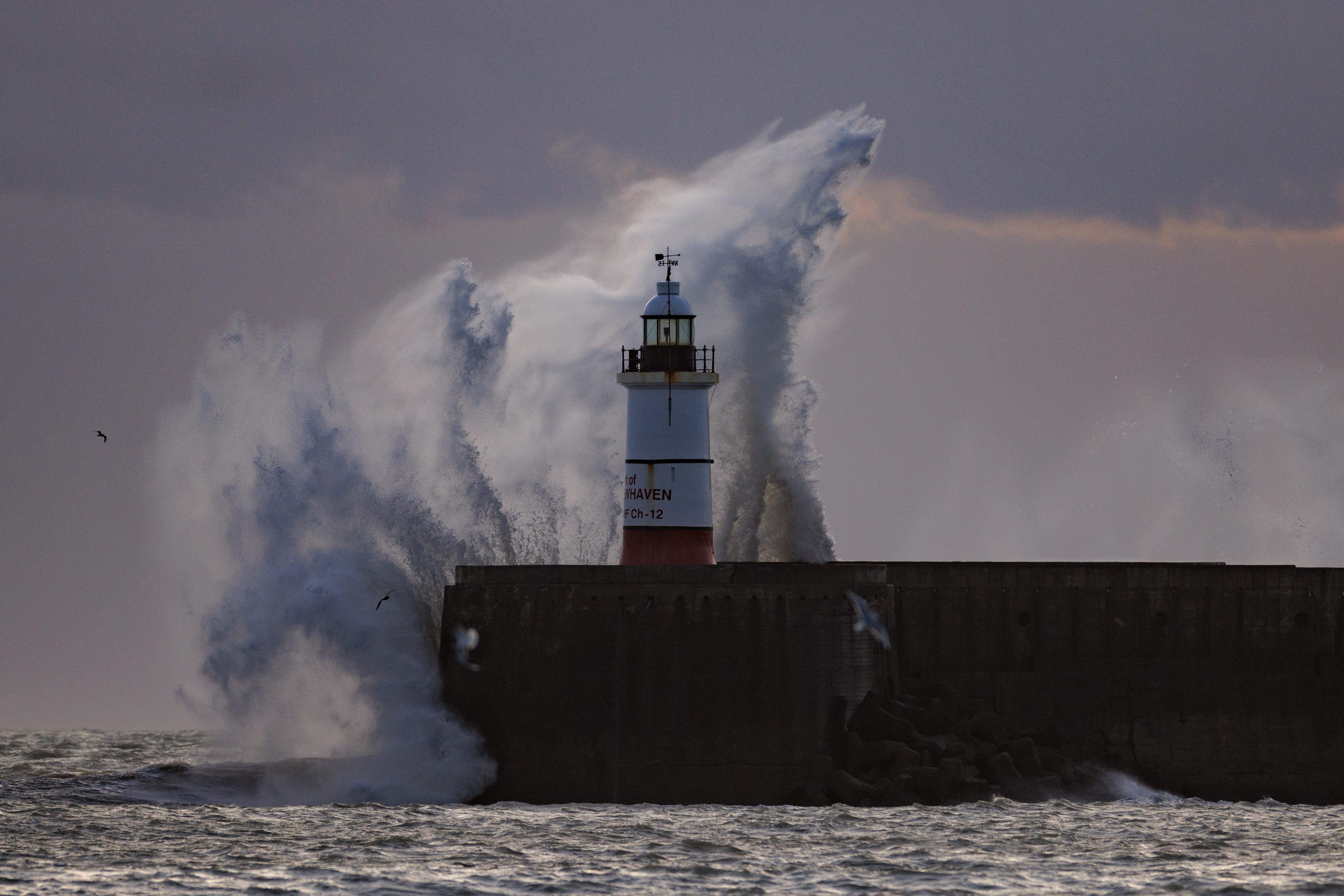Eine riesige Welle stürzt auf den Newhaven Lighthouse in East Sussex