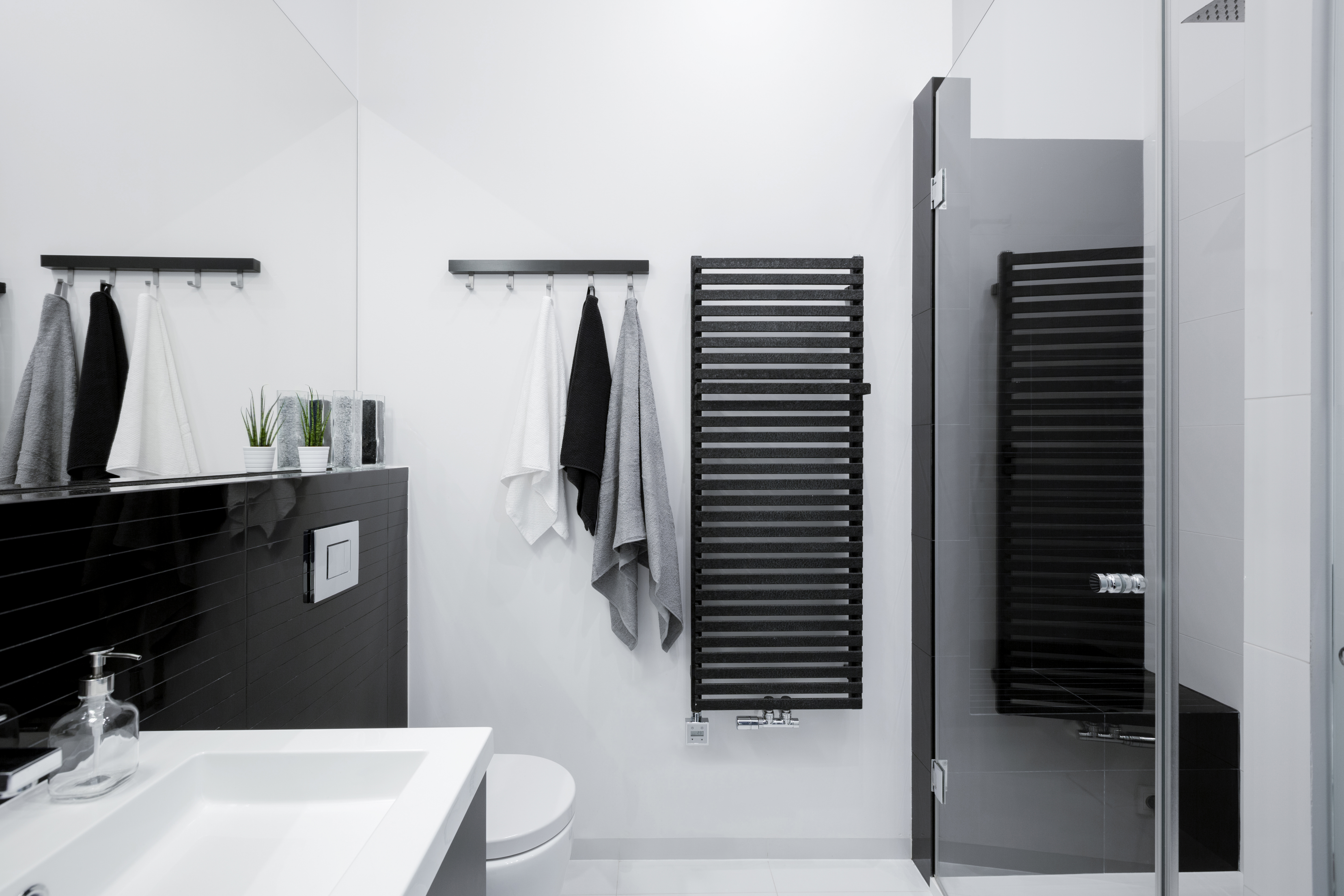 Schwarz in einem Badezimmer kann deprimierend wirken und sollte durch wärmere Töne wie ein klares Weiß ausgeglichen werden