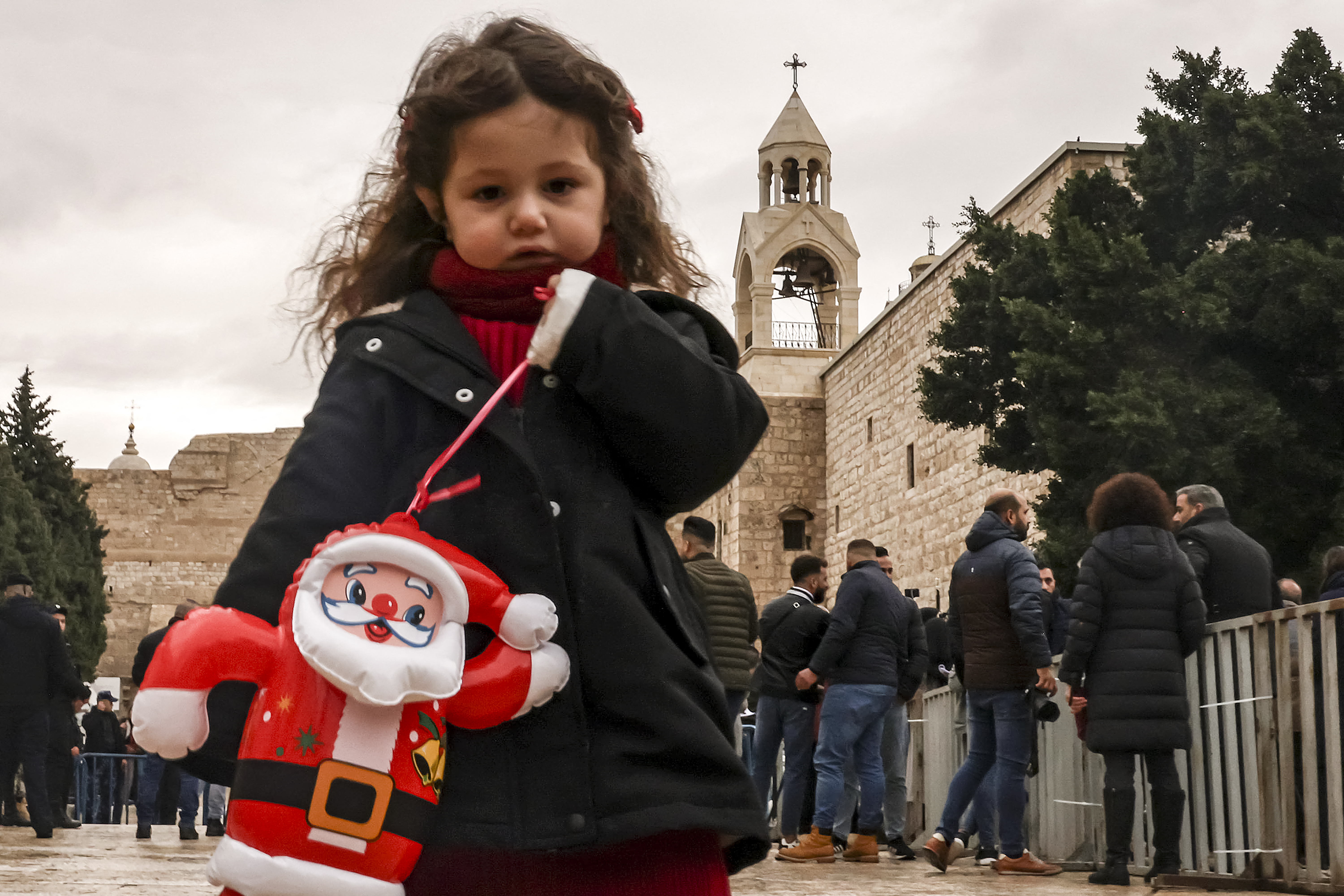 Ein Mädchen steht mit einer aufblasbaren Weihnachtsmannpuppe auf dem Krippenplatz vor der Geburtskirche