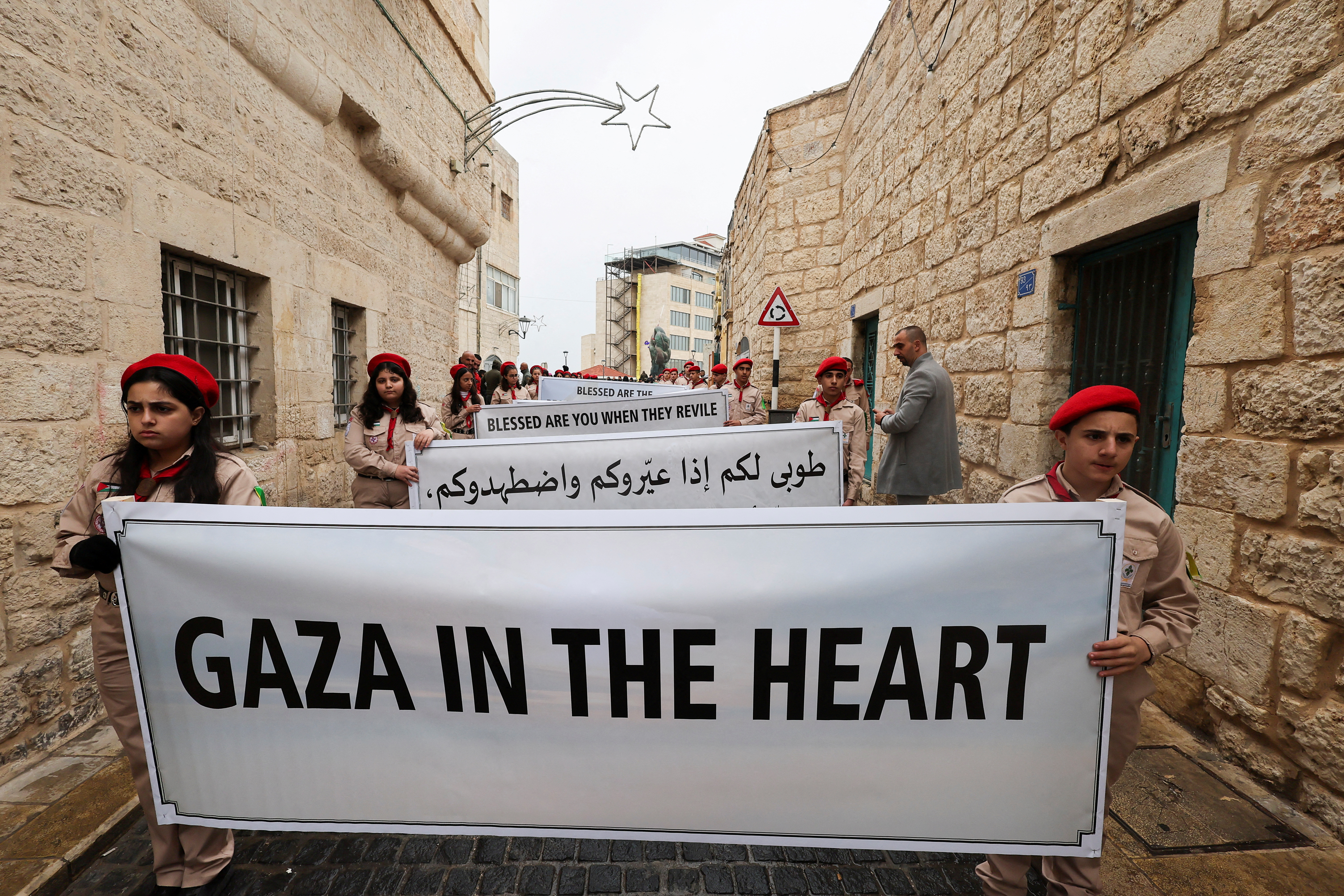 Junge Pfadfinder marschieren leise mit Schildern über den andauernden Krieg in Gaza durch Bethlehem