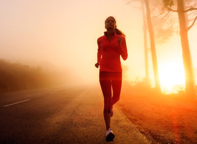 Fitness-Frau läuft frühmorgens im Freien, während die Sonne aufgeht