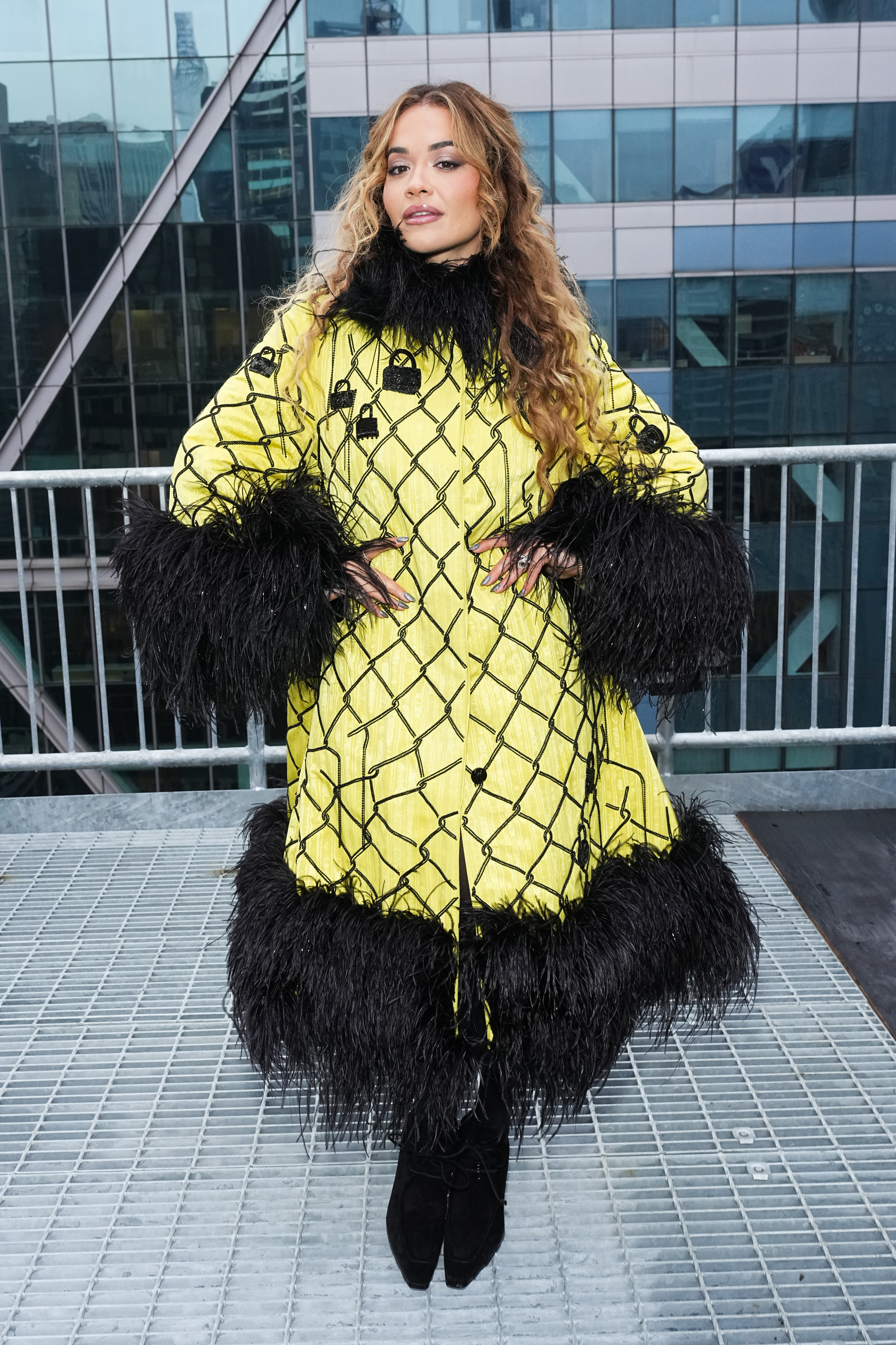 Rita Ora abgebildet in einem gelben Mantel mit Rüschenbesatz