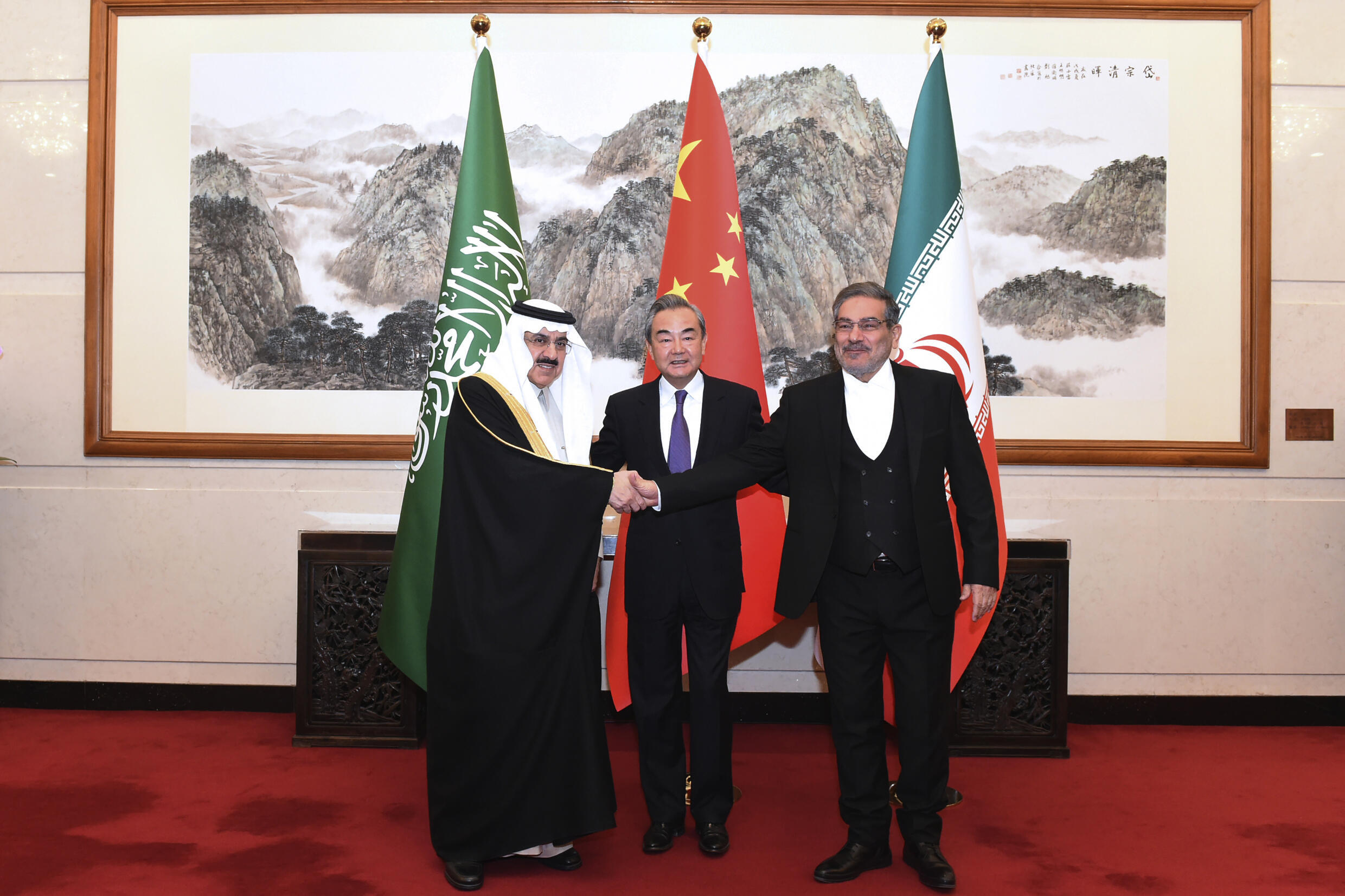 Ali Shamkhani, secretary of Iran's Supreme National Security Council (right) shakes hands with Saudi national security adviser Musaad bin Mohammed al-Aiban (left) joined by China's Wang Yi (center).
