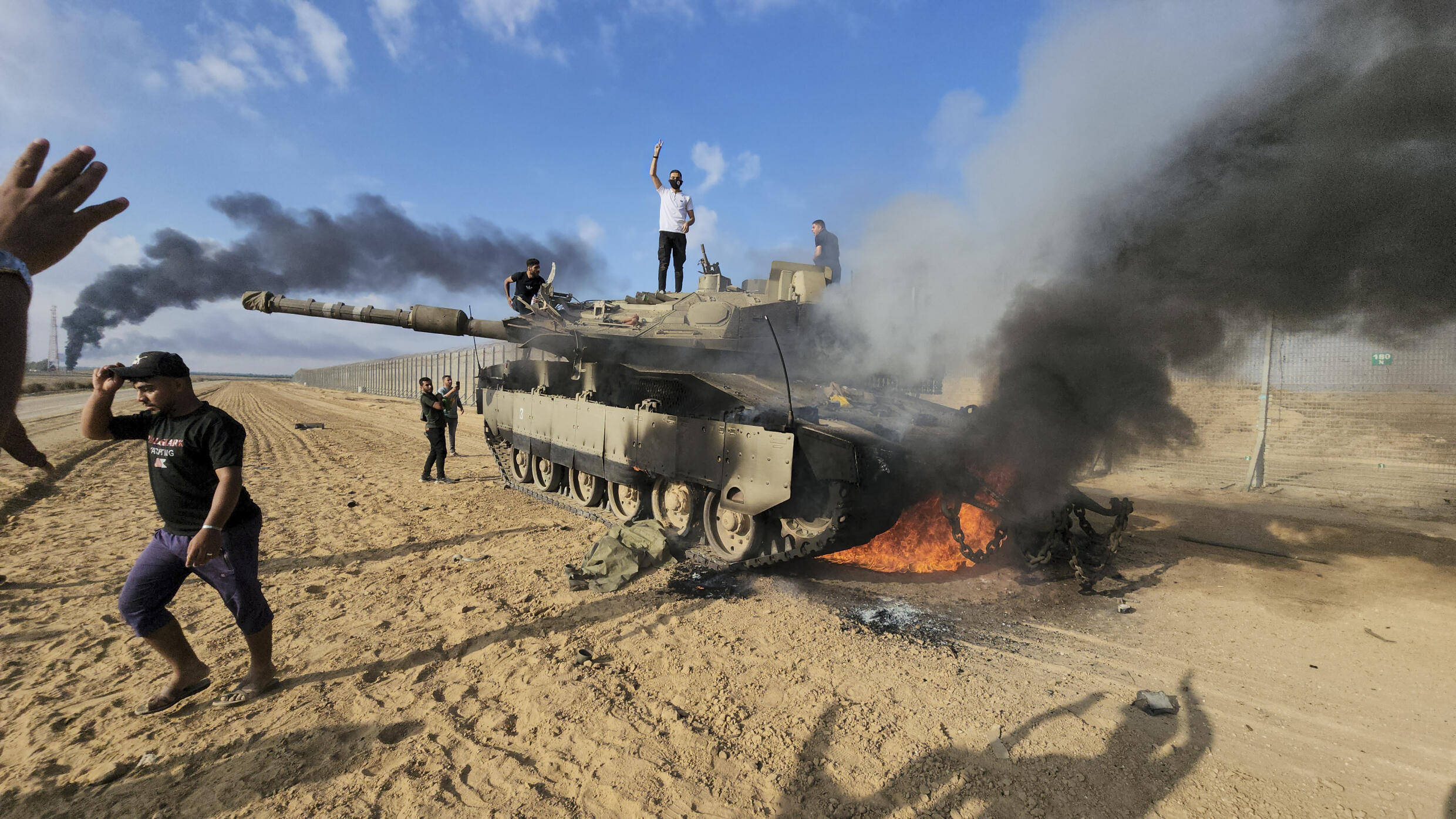 Palestinians near a destroyed Israeli tank in the Gaza Strip east of Khan Yunis on October 7, 2023.