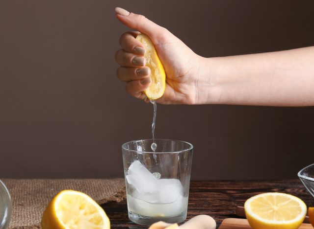 Frau drückt Zitrone in Glas Wasser