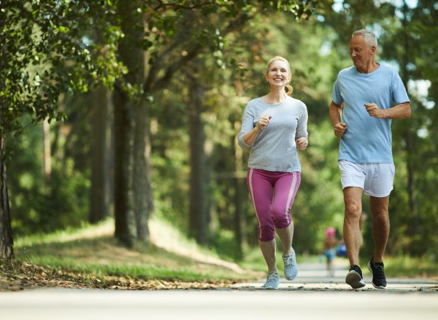 Paar mittleren Alters joggt im Freien, Vorstellung davon, was mit 50 gesünder ist, wenn man spazieren geht oder joggt