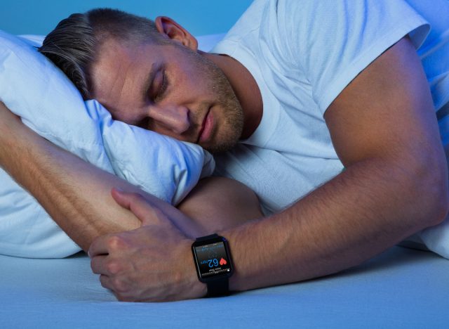 Fitter Mann mittleren Alters schläft und trägt einen Fitness-Schlaf-Tracker