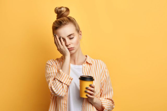 müde Frau hält Kaffee