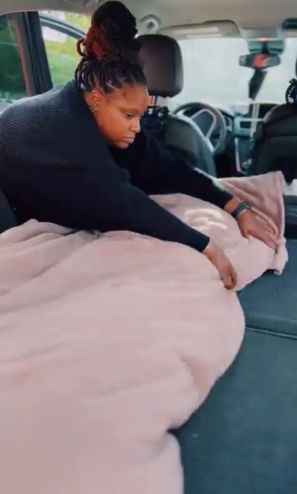 Die Frau macht ihr Bett, indem sie die Rücksitze ihres Autos flach macht