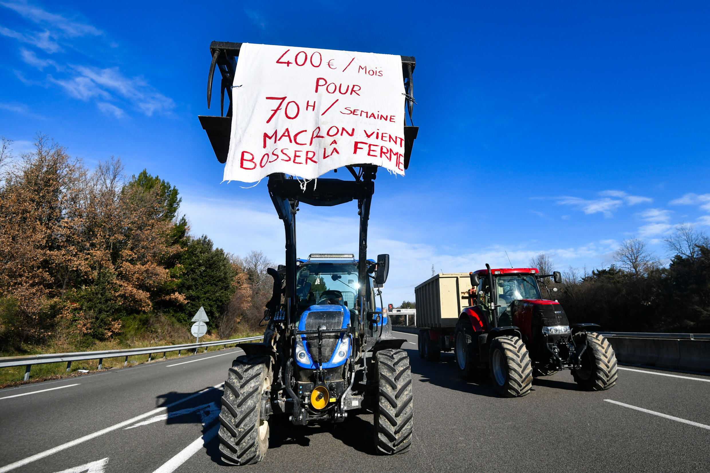 Ein Traktor trägt ein Banner mit der Aufschrift "400 Euro im Monat, für 70 Stunden pro Woche, kommt Macron zur Arbeit auf dem Bauernhof" im Südosten Frankreichs am 24. Januar 2024.
