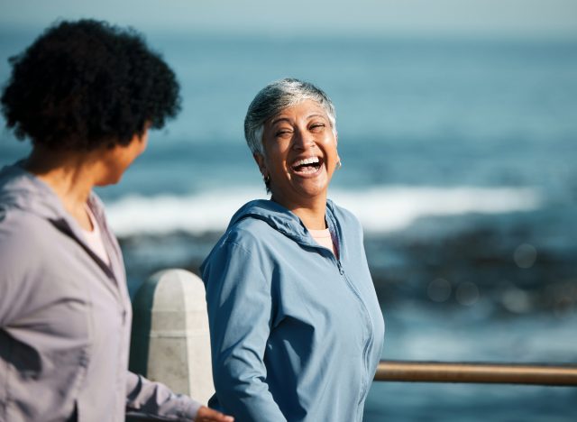 Glückliche reife Frau, die auf der Promenade am Meer spaziert, Konzept mit Tipps für ein längeres Leben