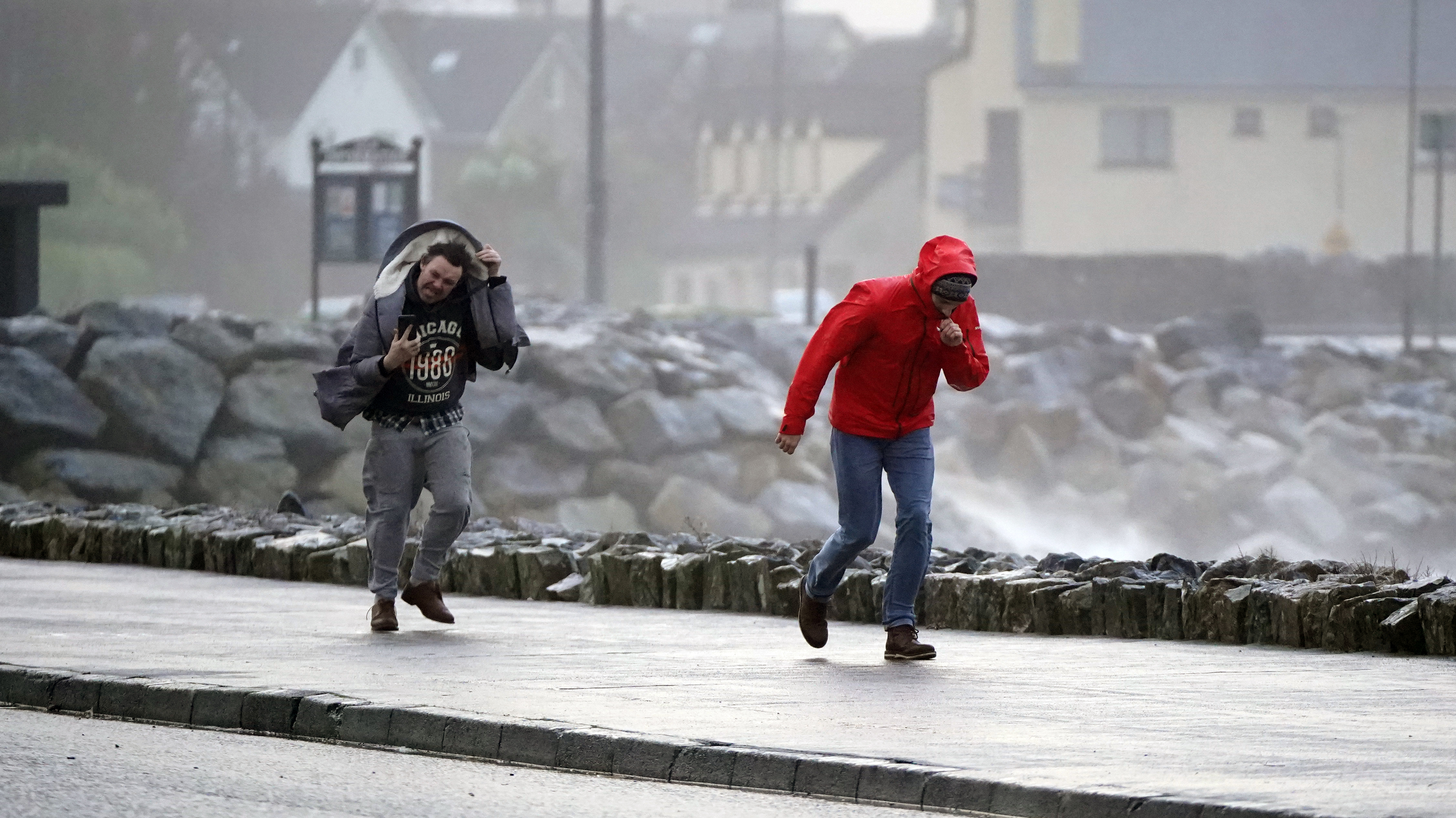 Menschen, die während des Sturms Isha bei starkem Wind in Salthill, Galway, spazieren gehen