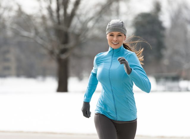 Frau rennt im Schnee, um die Gewichtszunahme im Urlaub loszuwerden