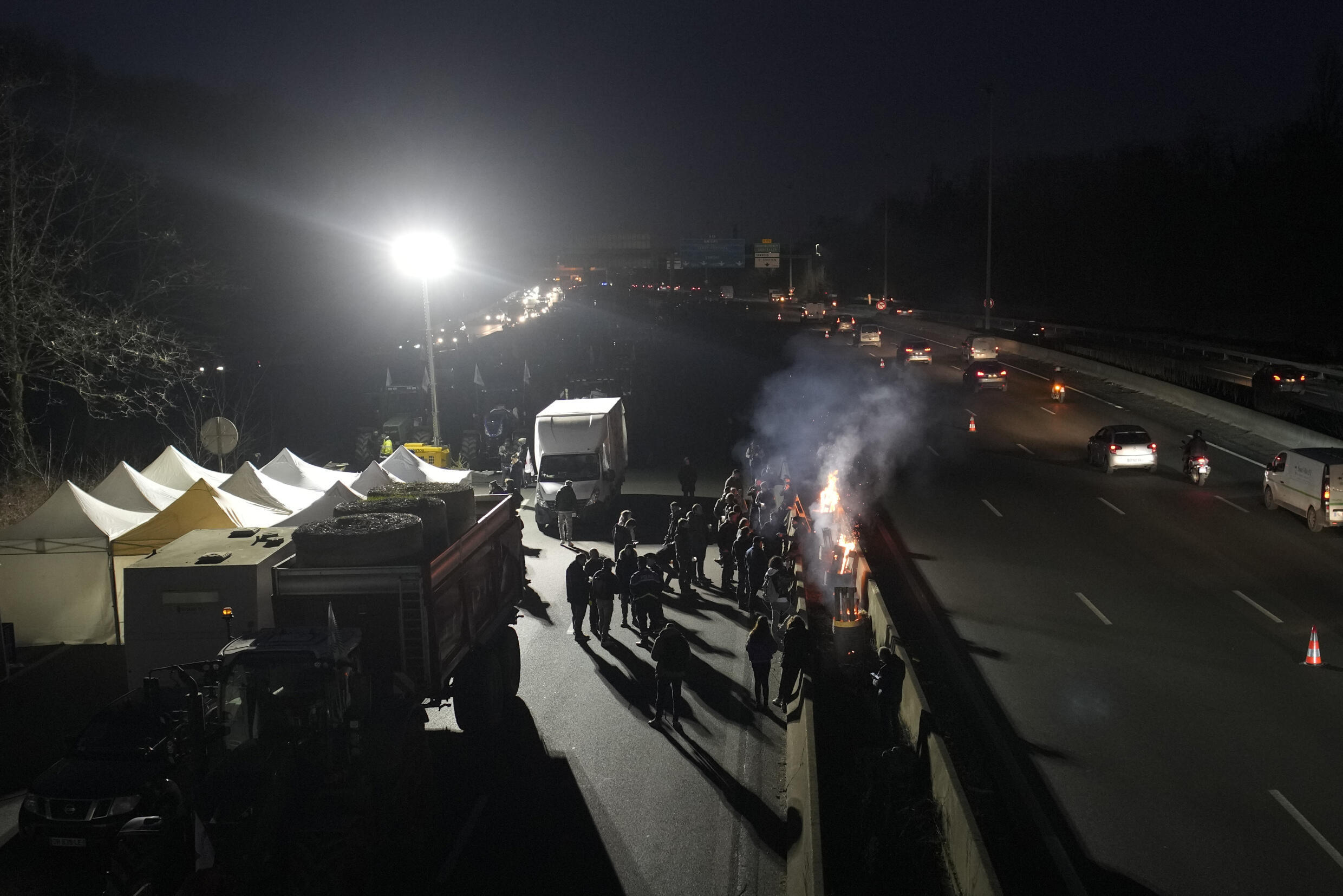 Bauern versammeln sich am 29. Januar 2024 an Lagerfeuern auf einer Autobahn in der Nähe von Argenteuil nördlich von Paris.