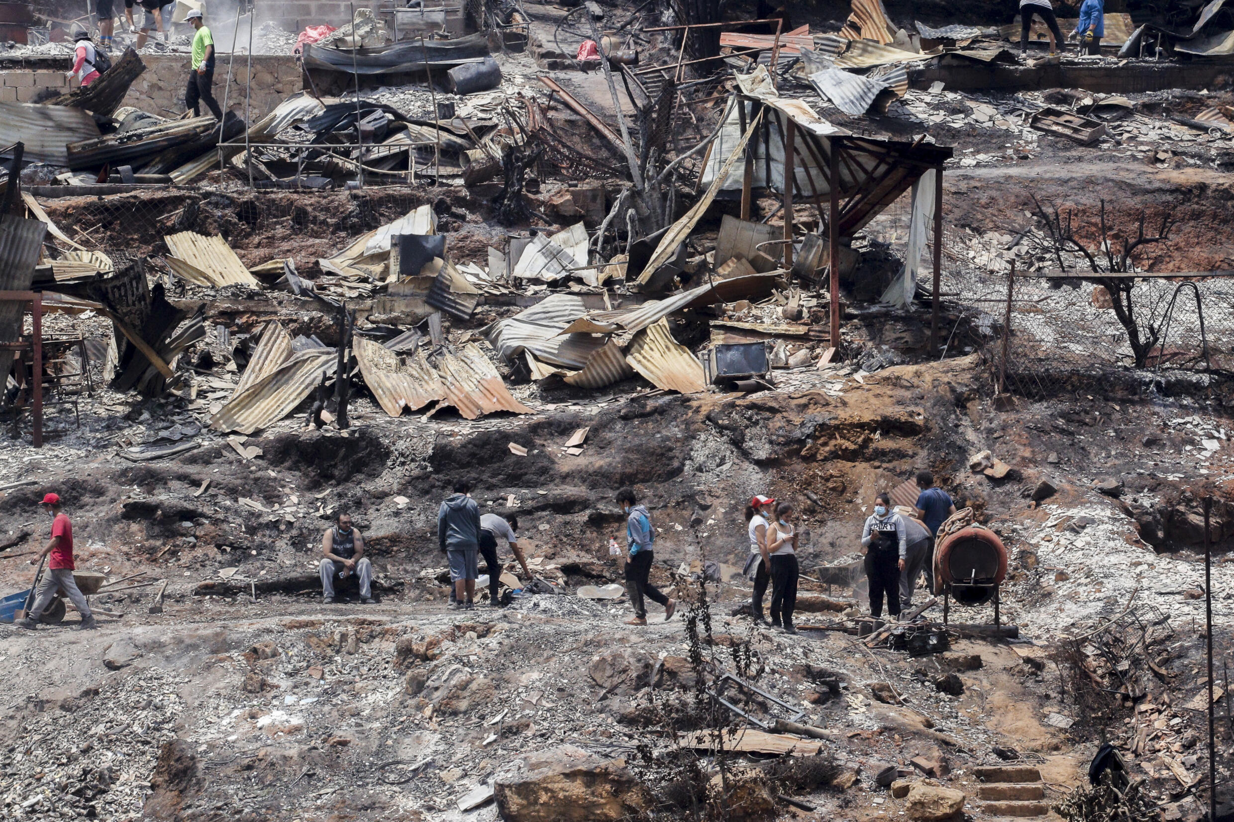 Einheimische reinigen die Trümmer ausgebrannter Häuser, nachdem Waldbrände ihr Viertel in Vina del Mar, Chile, am Sonntag, 4. Februar 2024, erreicht hatten.