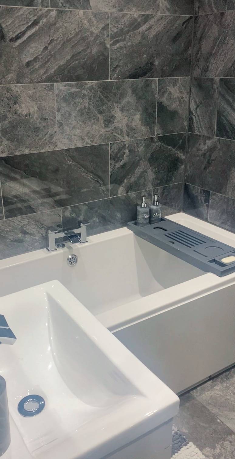 Das moderne Badezimmer verfügt über graue Fliesen und einen passenden Boden