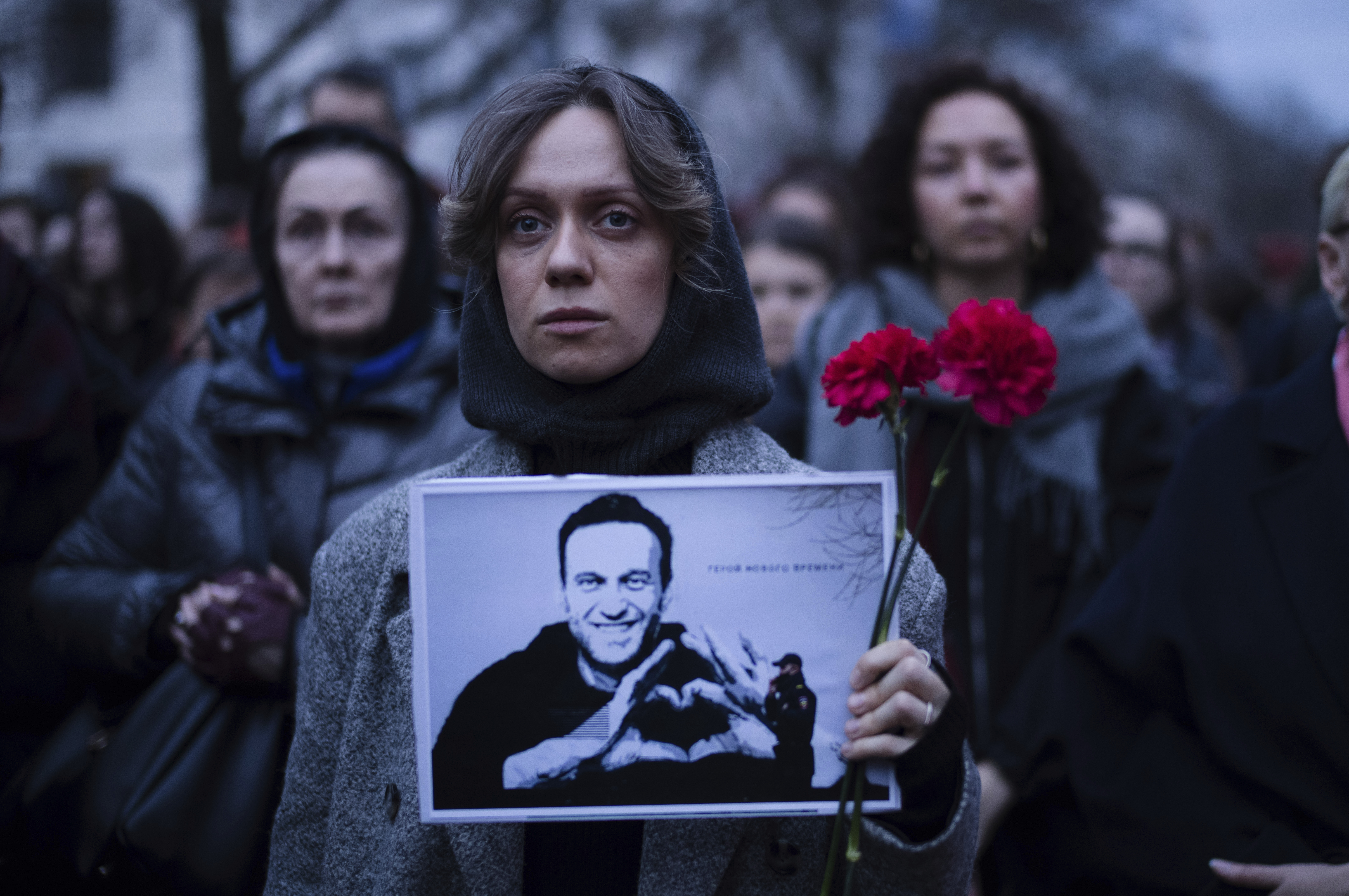 A woman holds flowers and a portrait of Navalny in front of the Russian embassy in Berlin, Germany