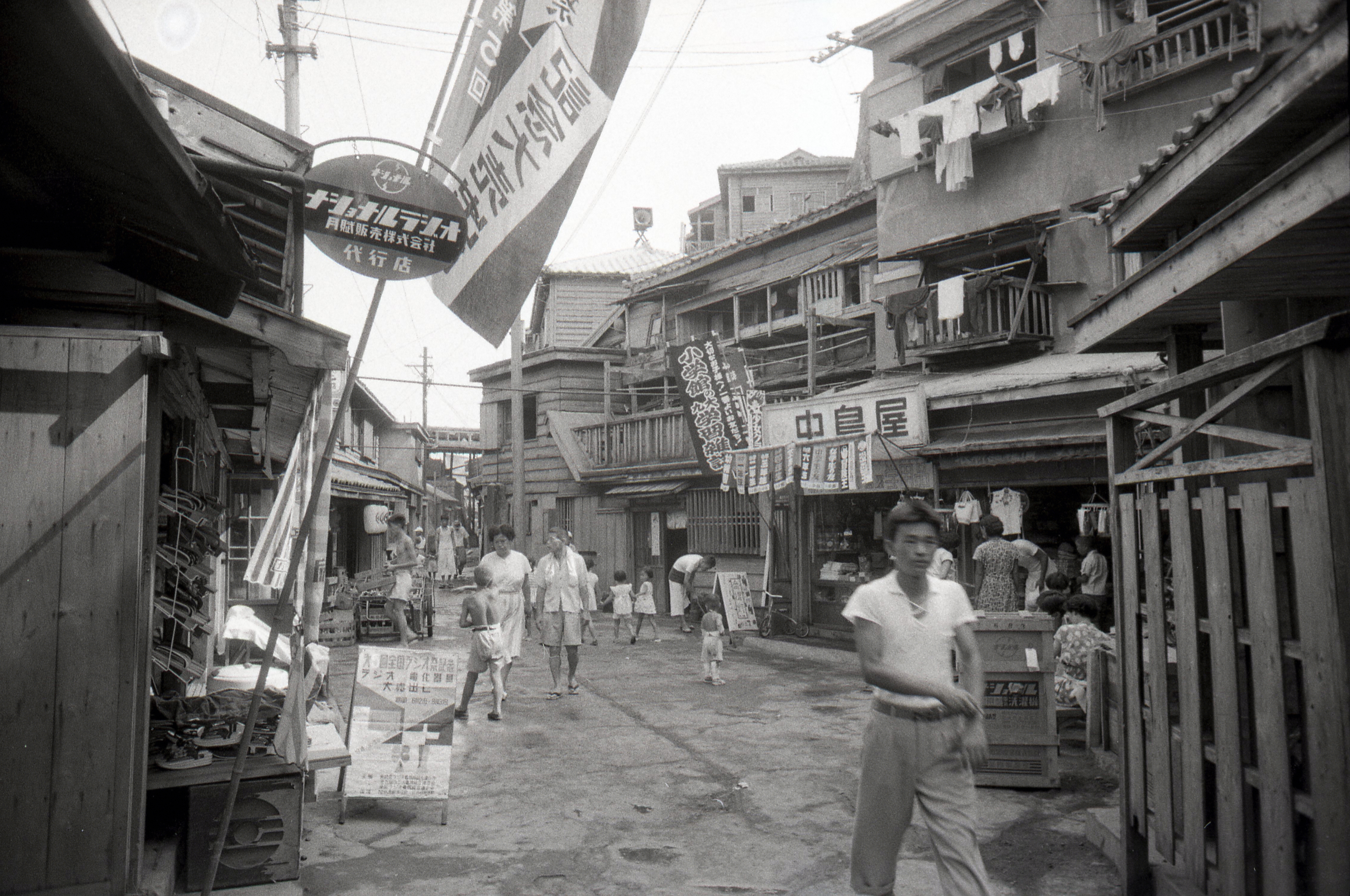 Menschen gehen am 12. August 1956 in Takashima, Nagasaki, durch eine Einkaufsstraße in Hashima