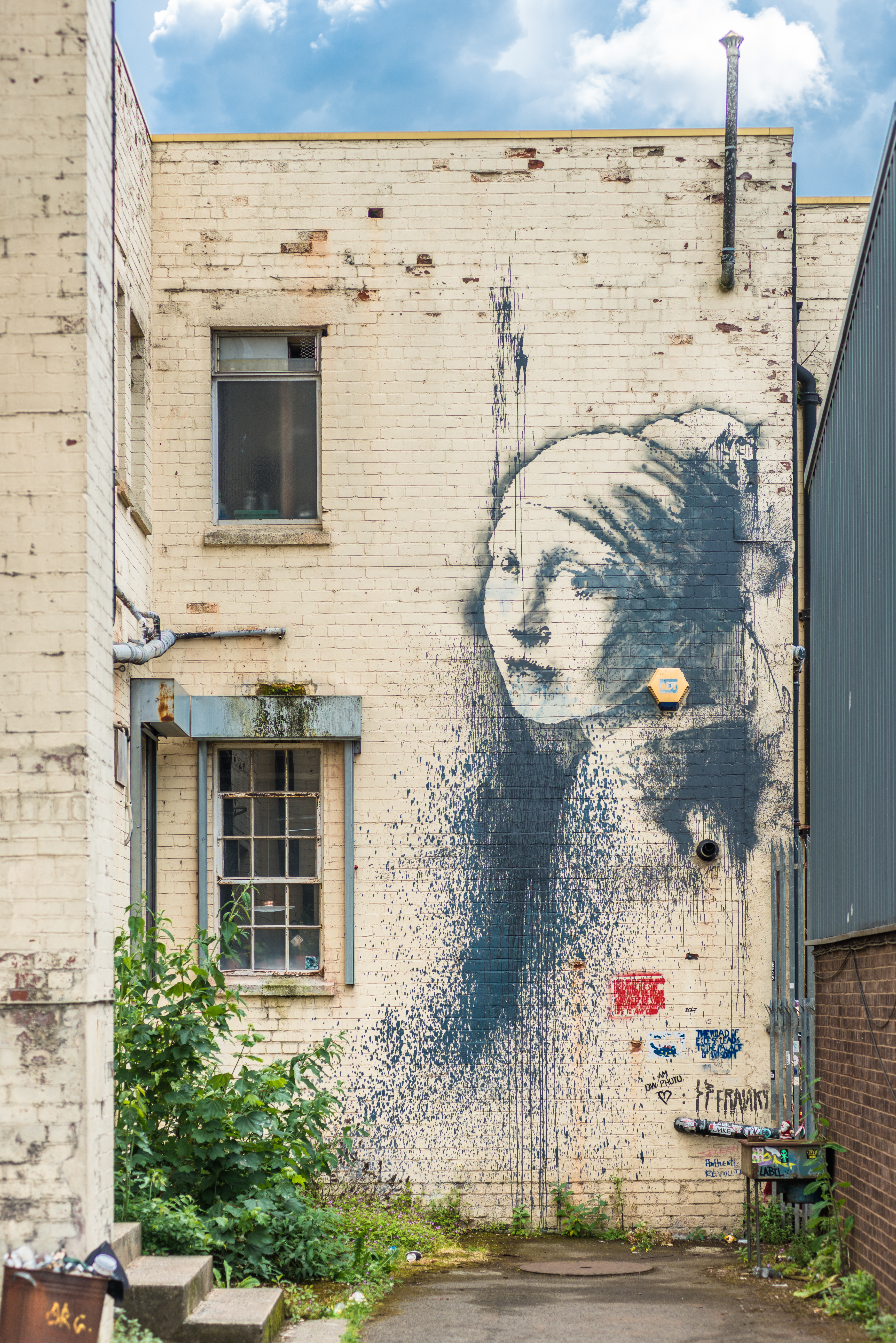 „Mädchen mit durchbohrtem Trommelfell“ von Banksy an der Wand einer Gasse in Albion Docks, Bristol