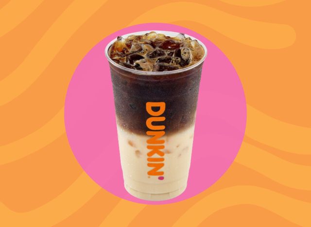 Cup of Dunkin' iced macchiato on a pink and orange background. 