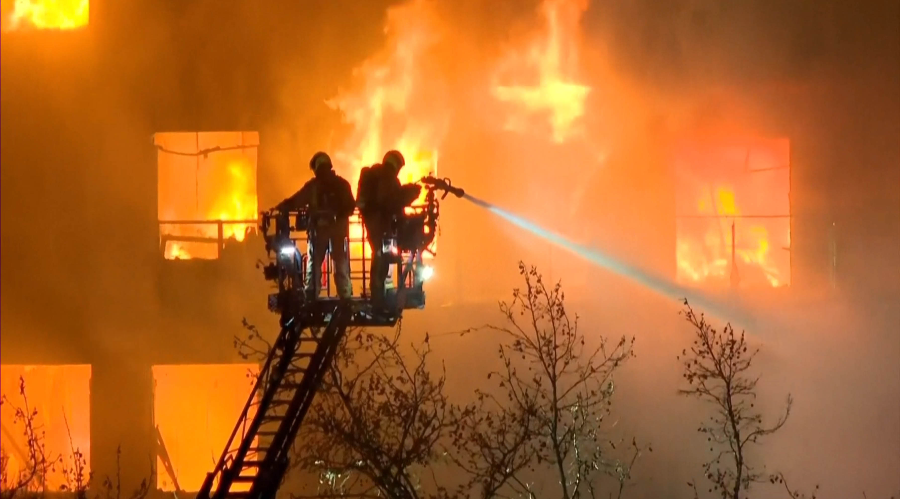 Zwei Feuerwehrleute löschen die Flammen verzweifelt mit Wasser
