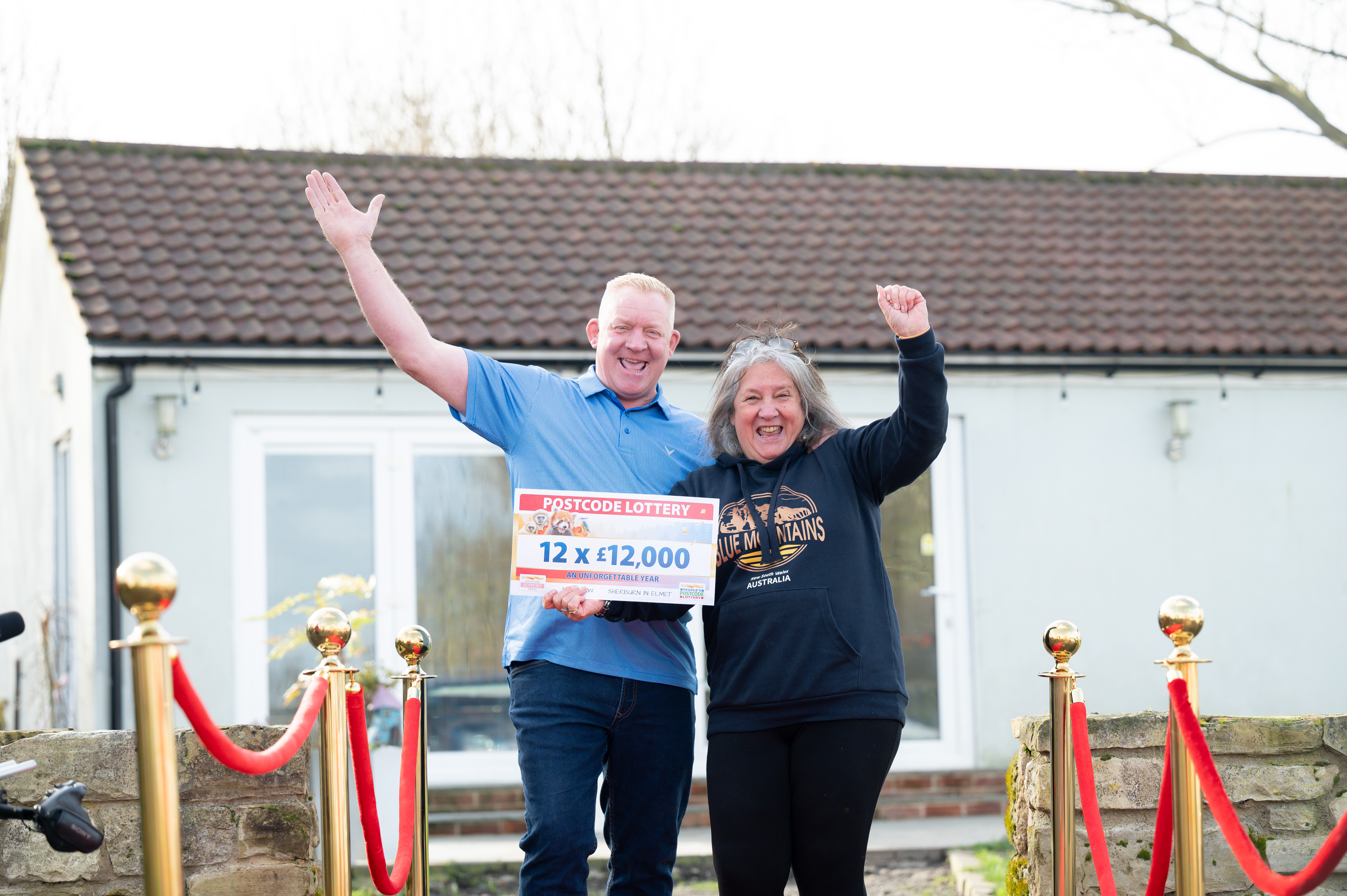 Die Gewinner der People's Postcode Lottery, Andy und Meg, posieren mit ihren Gewinnen
