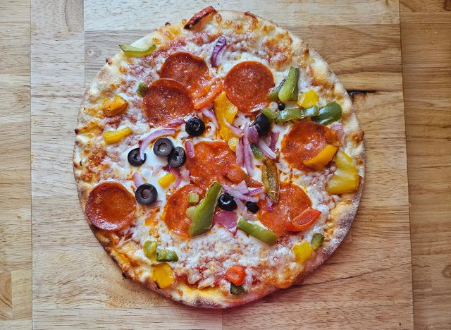 Glutenfreie, ungehärtete Peperoni-Pizza mit Paprika, roten Zwiebeln und schwarzen Oliven auf einer Blumenkohlkruste