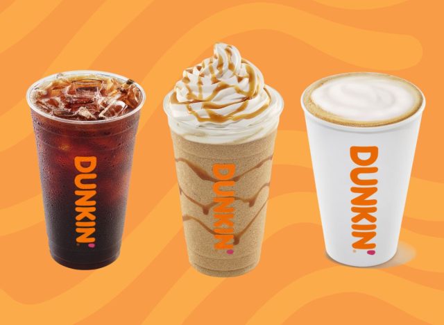 Drei Tassen Dunkin'-Getränke auf orangefarbenem Hintergrund