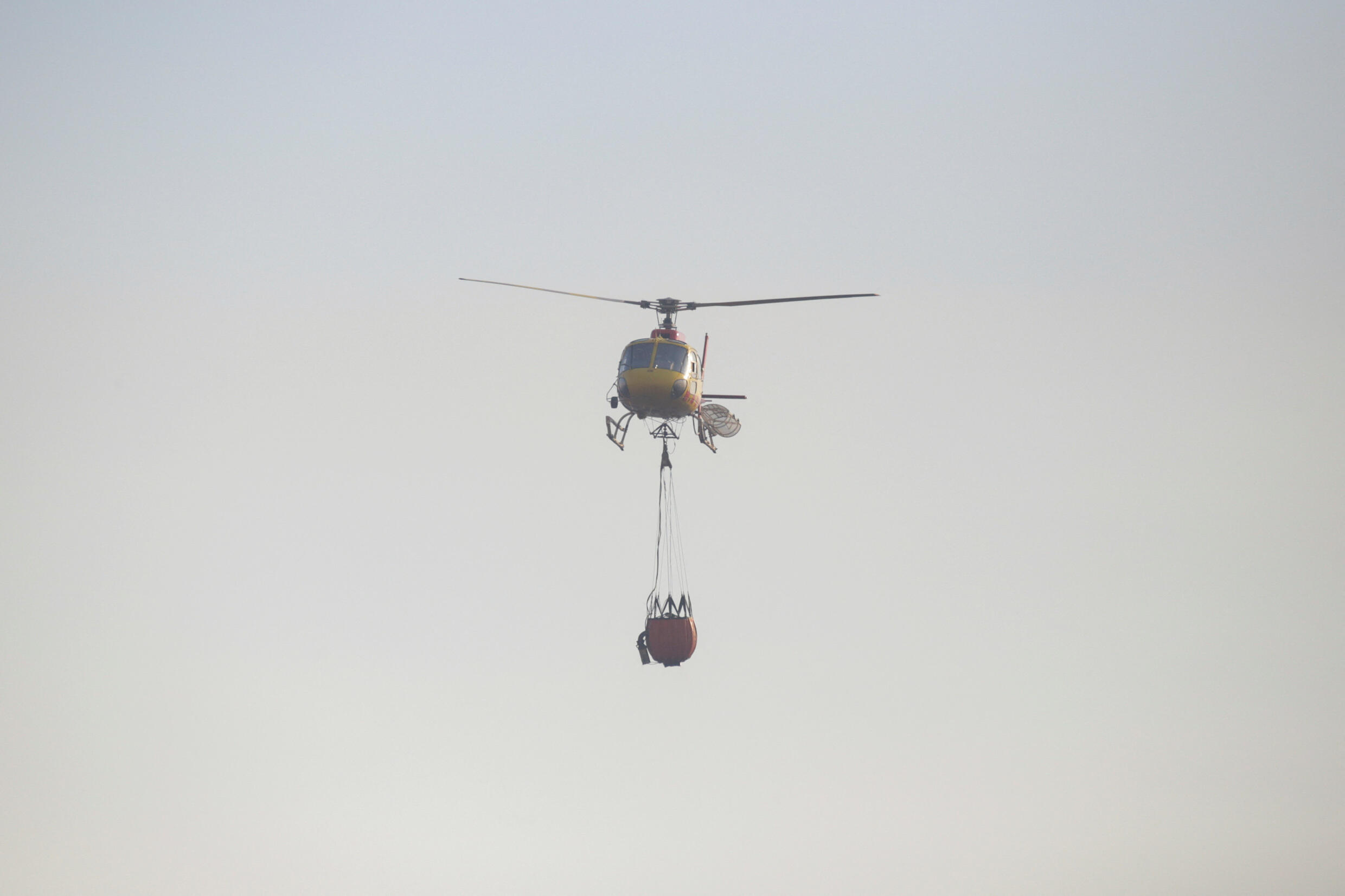 Ein Hubschrauber mit einem Wassereimer fliegt über ein verbranntes Gebiet, um das Feuer während der Ausbreitung der Waldbrände in Vina del Mar, Chile, am 3. Februar 2024 zu löschen.