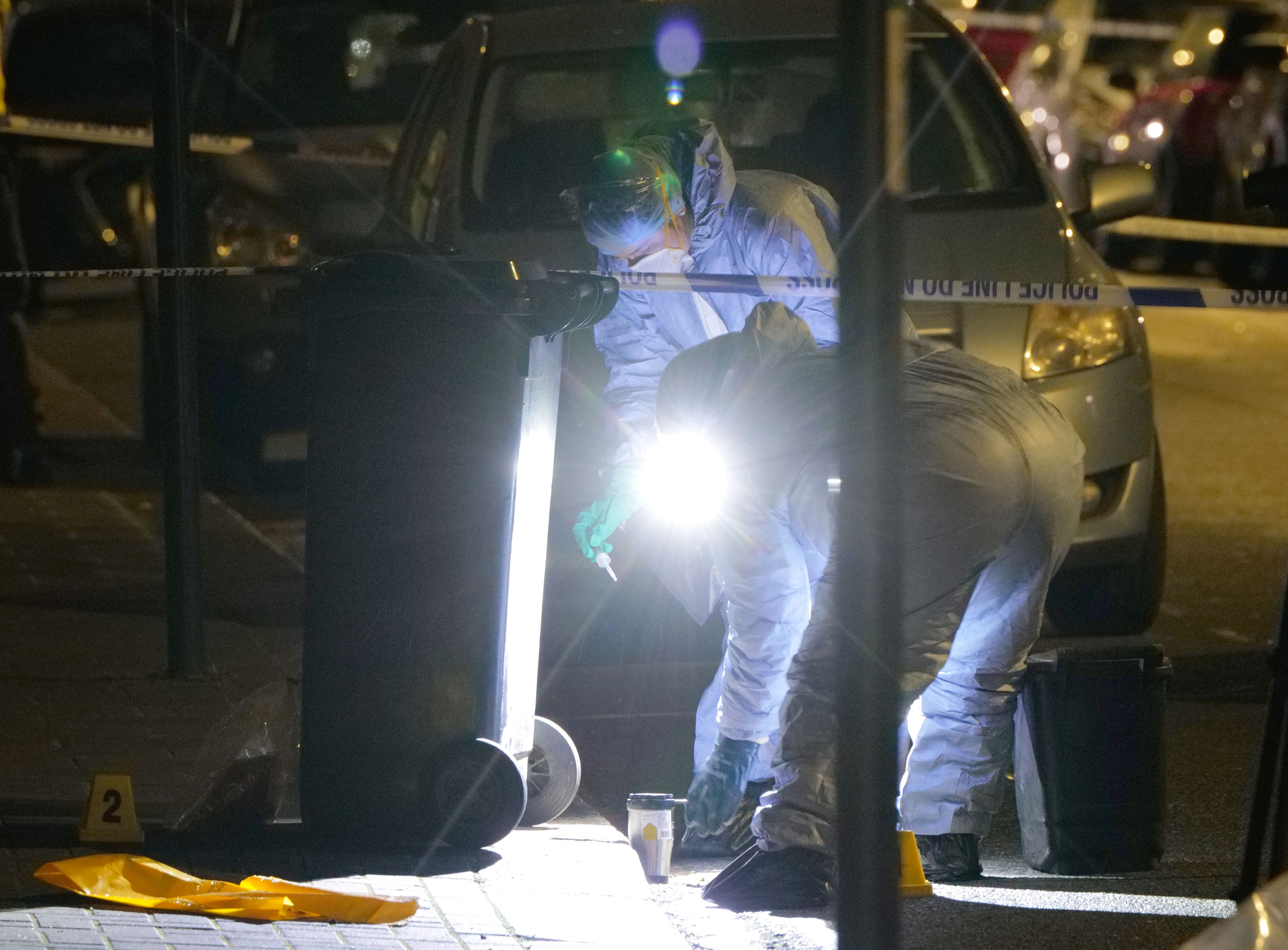 Polizisten untersuchen eine am Tatort zurückgelassene Kaffeetasse