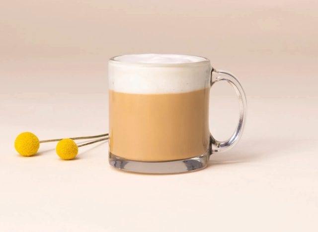 Eine Tasse Starbucks Blonde Vanilla Latte auf einem schlichten Hintergrund mit gelber Garnitur.