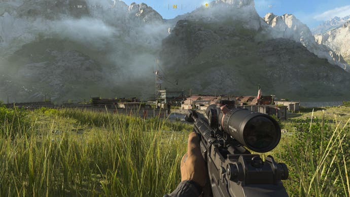 Modern Warfare 3-Screenshot des Spielers mit einem Scharfschützengewehr auf einer Wiese mit Blick auf einen Außenposten mit riesigen Bergen im Hintergrund