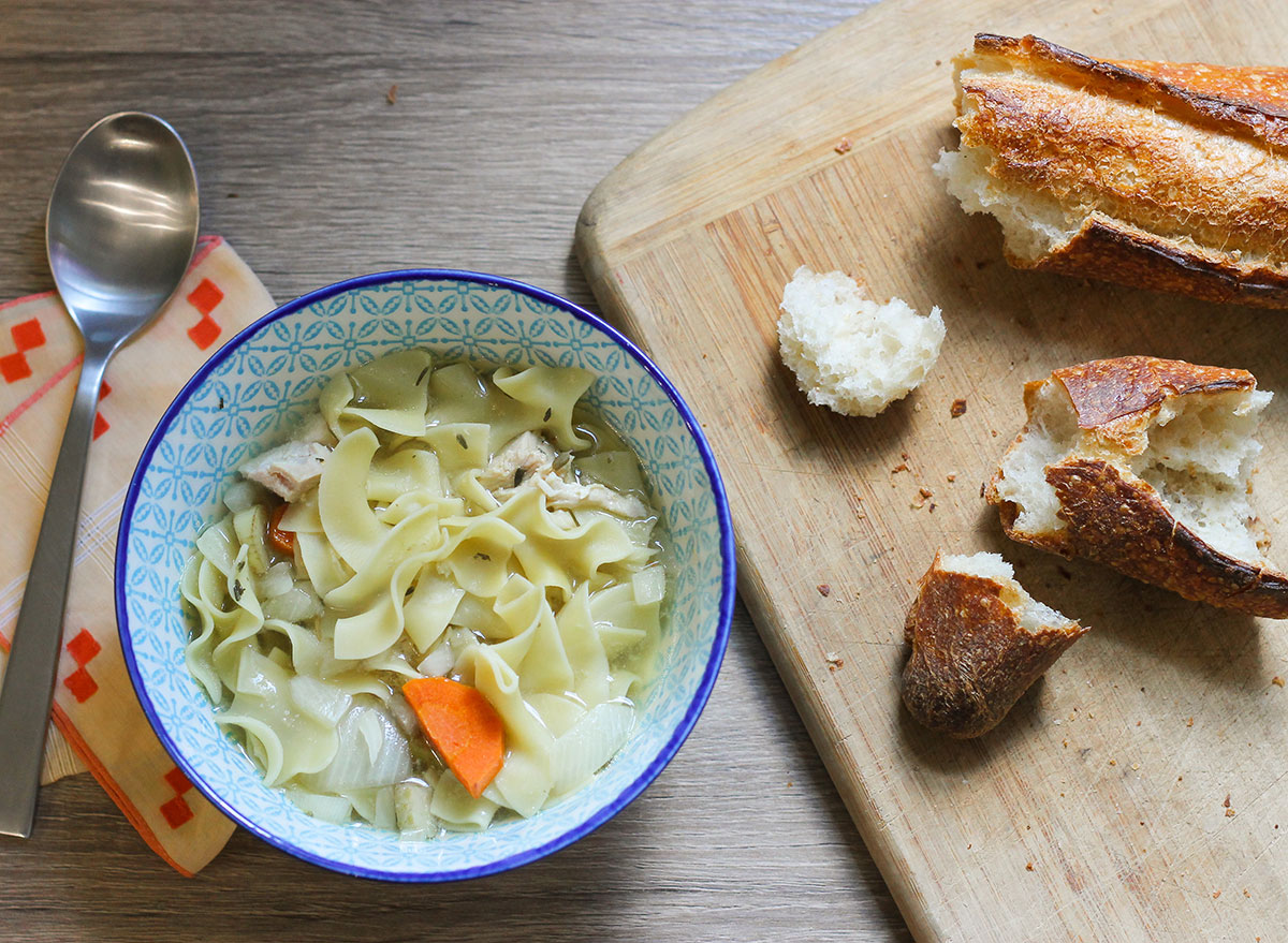 Crock Pot Hühnernudelsuppe mit Brot auf einem Tisch.