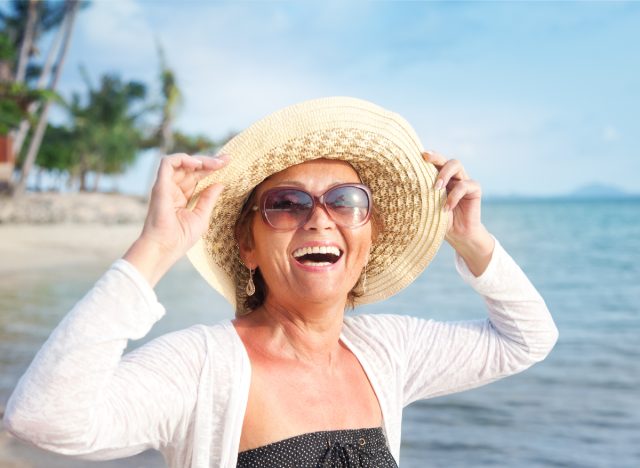 Glückliche ältere Frau, die am Strand lächelt