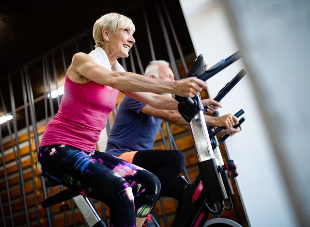 Zwei ältere Erwachsene machen Indoor-Cycling im Fitnessstudio