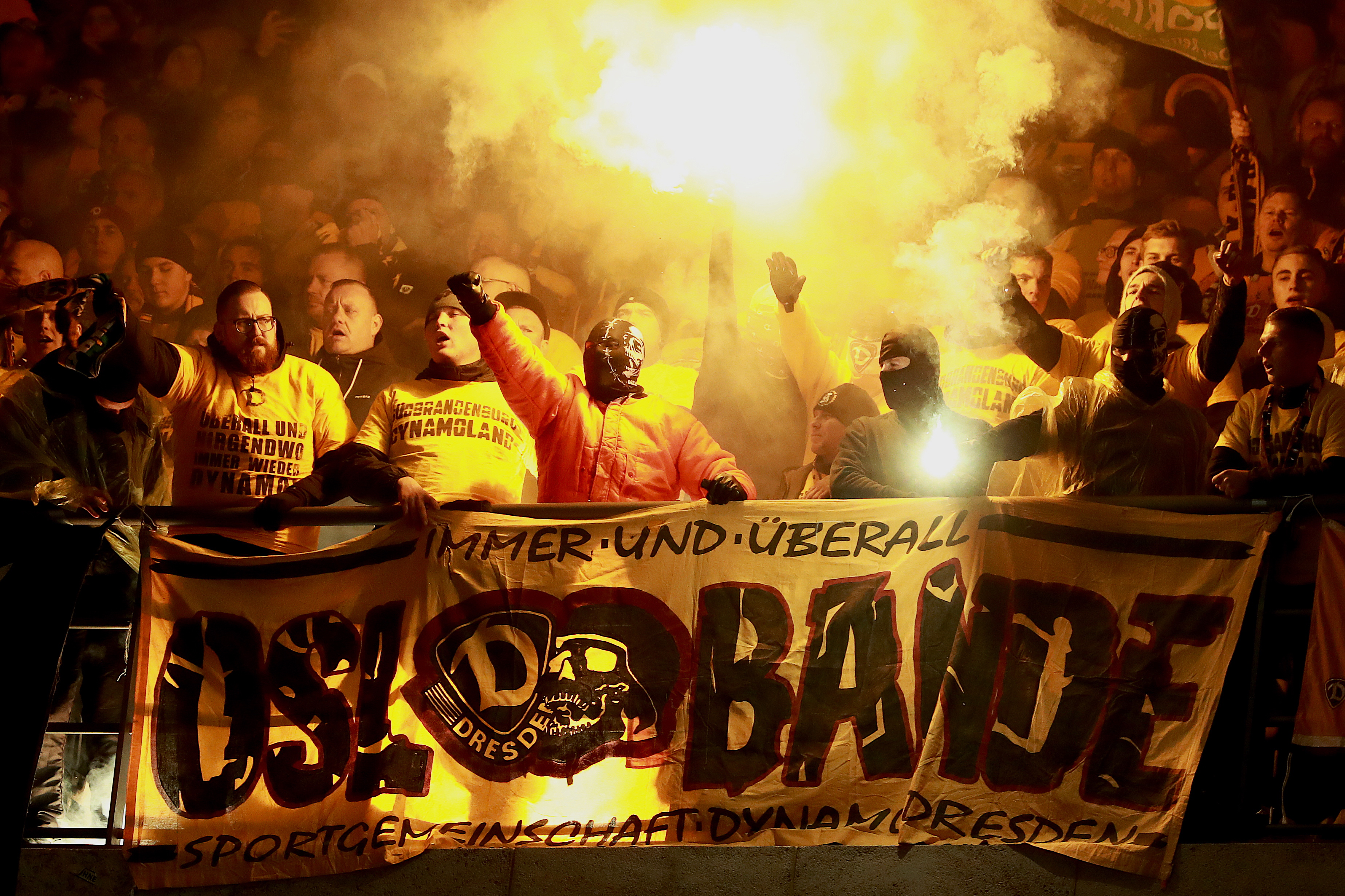 Maskierte Fans von Dynamo Dresden feuern Leuchtraketen ab