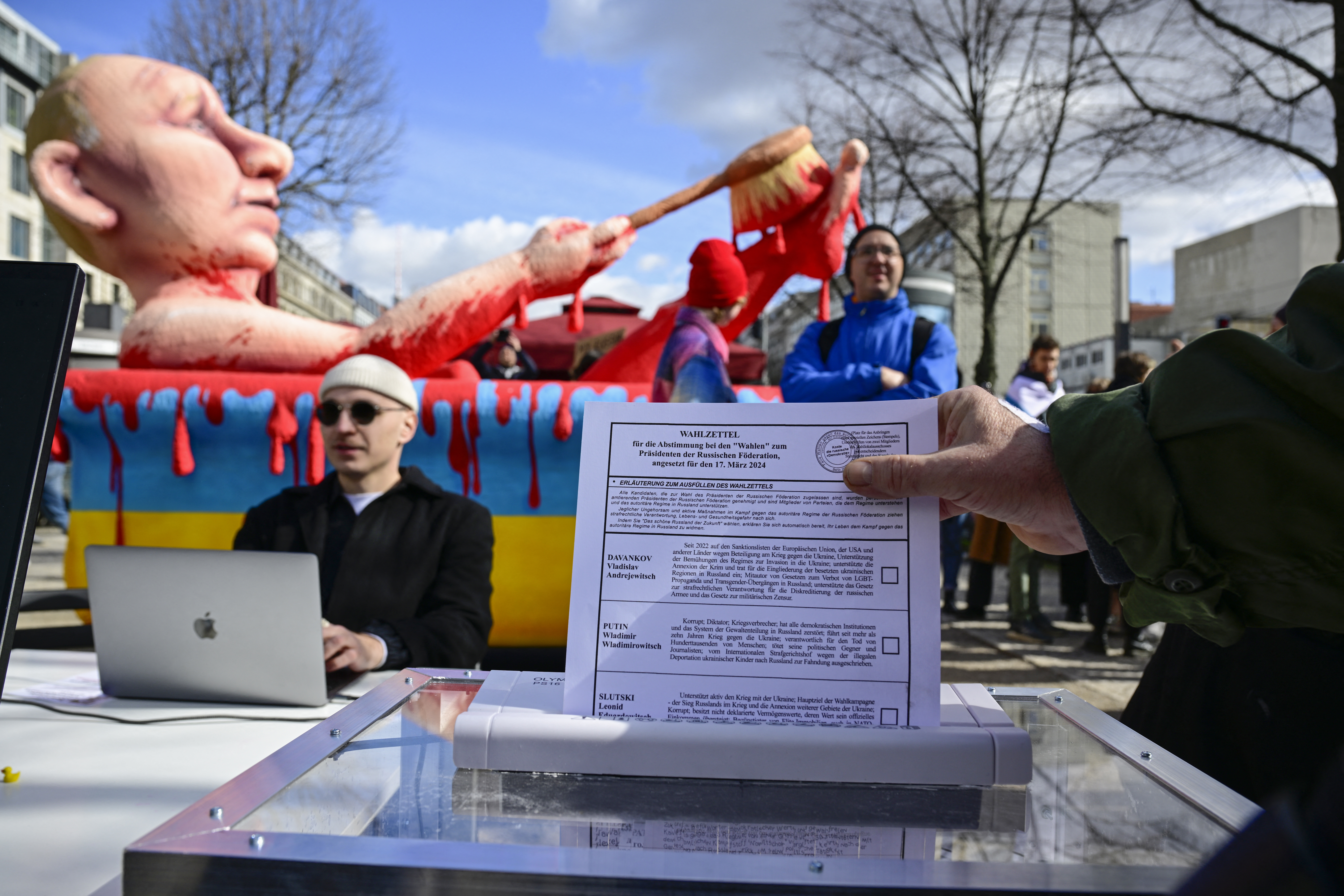 Ein Demonstrant wirft in Berlin einen Stimmzettel in einen Aktenvernichter