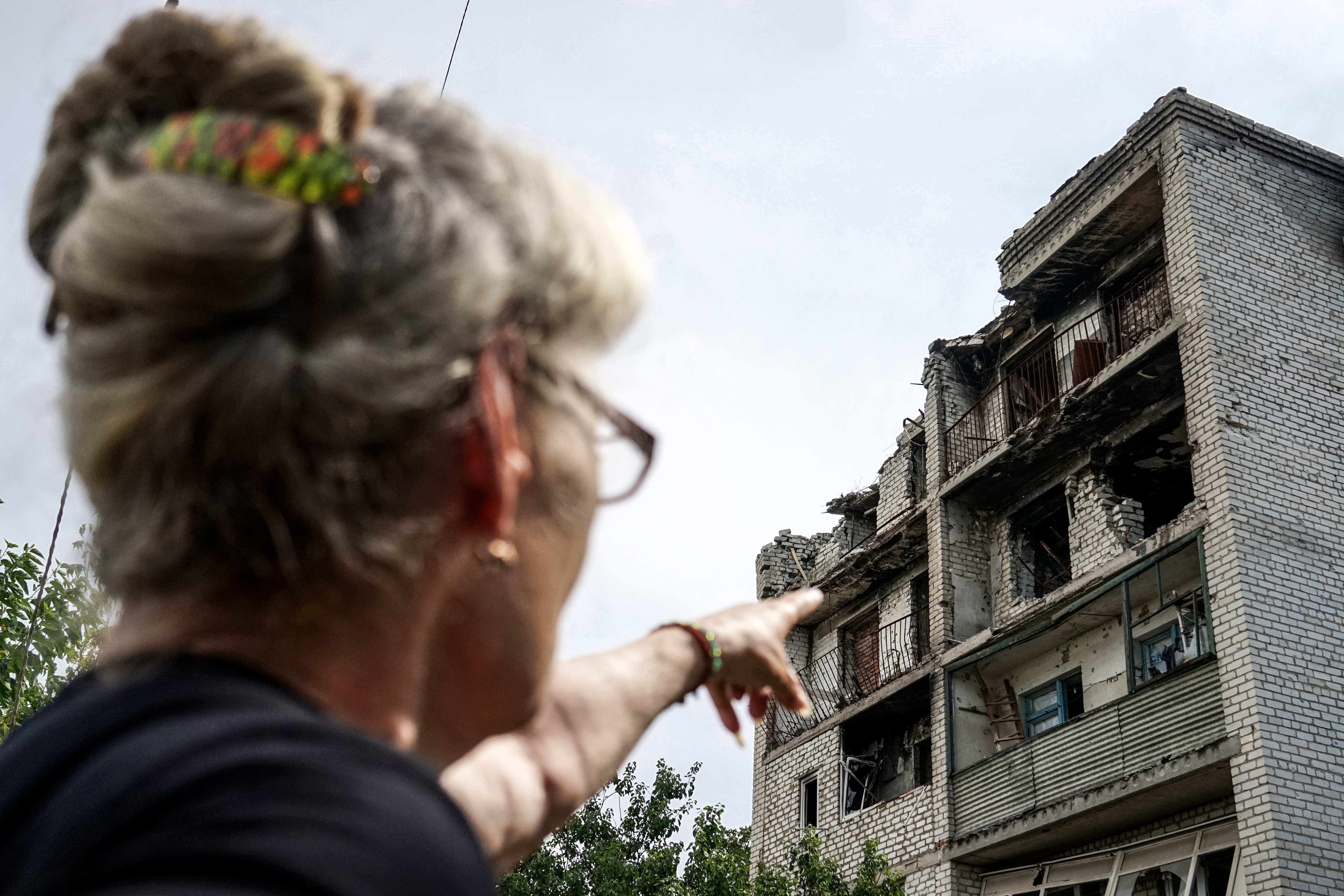 Eine ortsansässige Frau zeigt auf ihre Wohnung, die durch einen russischen Raketenangriff zerstört wurde