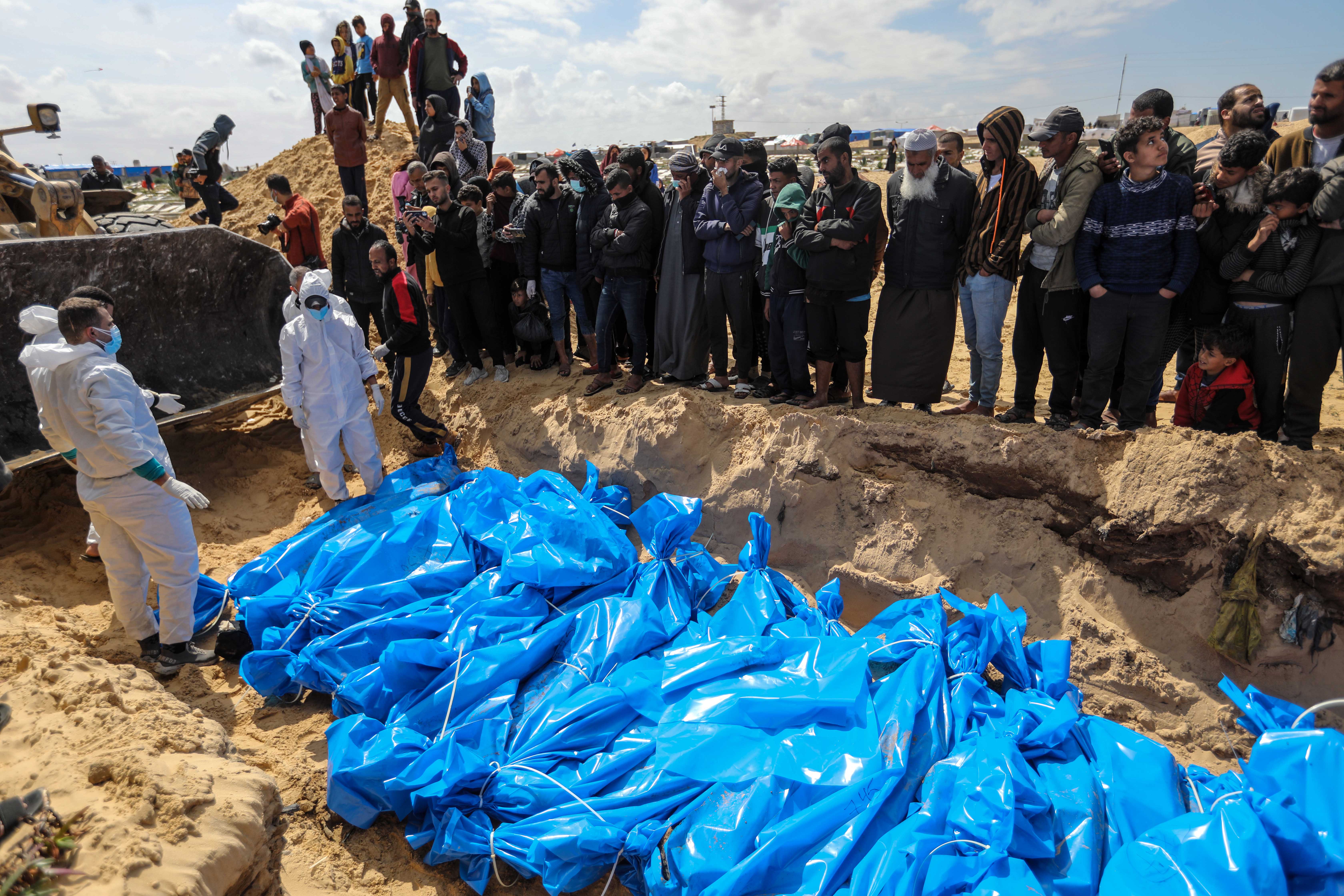 Menschen umzingeln ein Massengrab in Gaza, um zuzusehen, wie Leichen begraben werden