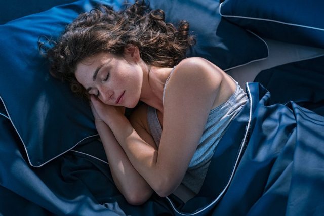 Frau schläft nachts friedlich im Bett