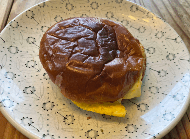 Panera-Wurst-Ei-Käse-Brioche-Sandwich auf einem bedruckten Teller. 