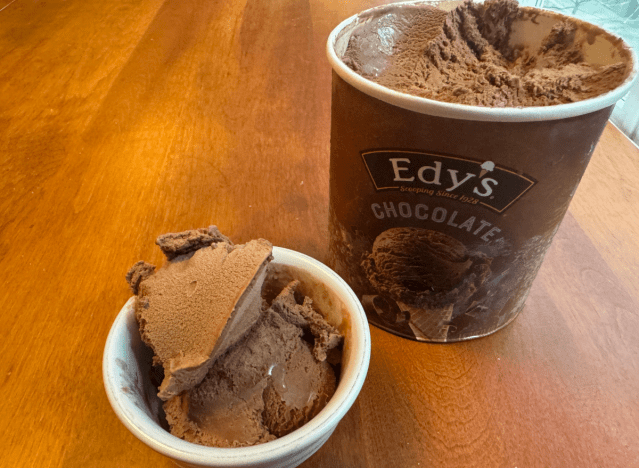 Ein Pint Edy's Schokoladeneis offen auf einem Tisch mit einer Schüssel Eis.
