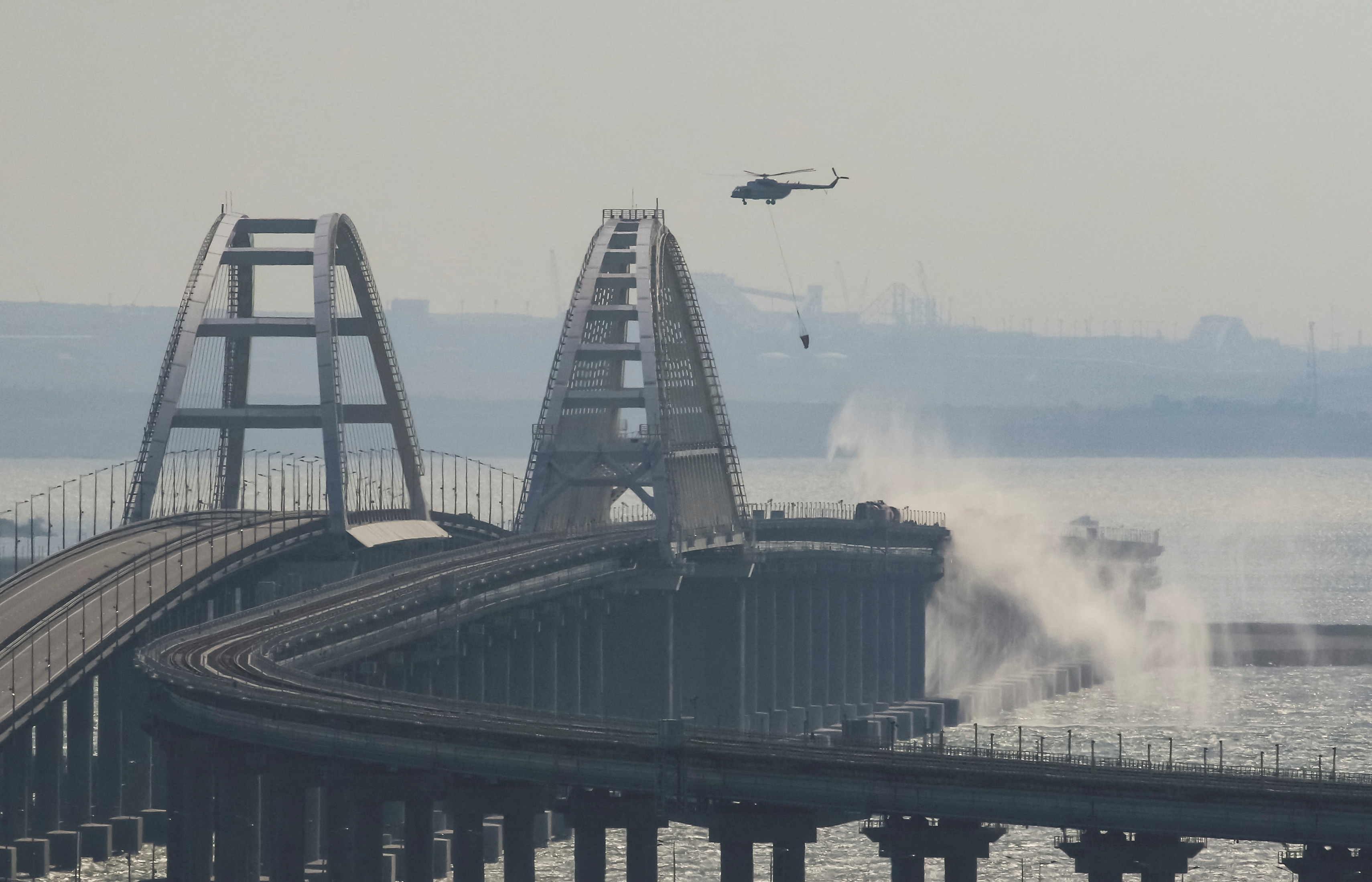 Helicopters douse the broken bridge with water to put out the flames following Ukraine's sabotage attack - one they are likely looking to replicate on a bigger scale