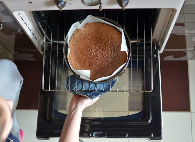 Frau holt Kuchen aus dem Ofen