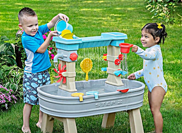 Kinder spielen auf einem Wassertisch.