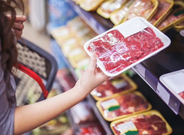 Frau hält verpacktes Fleisch im Supermarkt