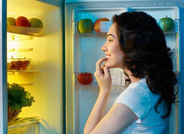 Frau öffnet und schaut in den Kühlschrank, Konzept des besten Snacks, um Bauchfett zu verlieren